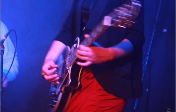 close-up van een gitariste onder blauwe spotlights